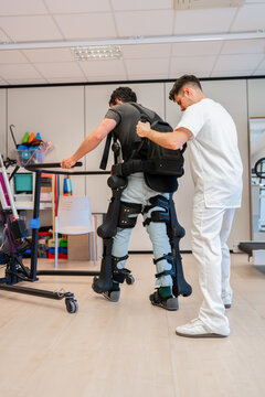 Doctor assisting patient using exoskeleton robotic legs to walk