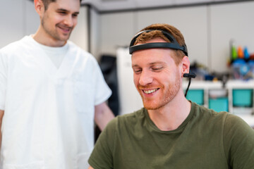 Doctor assisting smiling patient wearing brainwave scanning headset