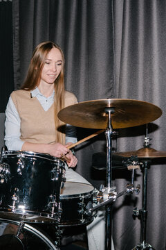 A woman learning to play the drums.