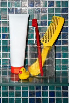 Bathroom shelf with white tube, red toothbrush and yellow hairbrush,