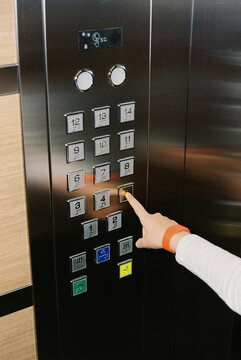 Teenager's hand wearing hotel bracelet pressing elevator button.
