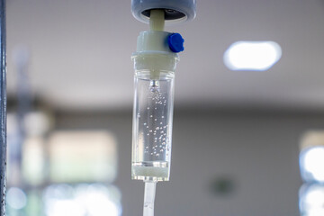 Close-up of an IV drip with visible fluid and bubbles, suggesting a hospital setting. Medical...