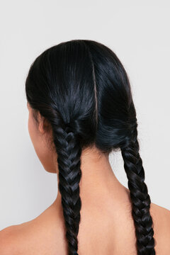 Back View of Woman with Long Braided Hairstyle on Light Background
