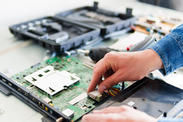 Close-up of electronic technician installing component on circuit board of broken television set...