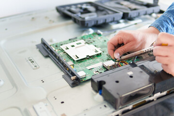 Close up of Hands working on electronic circuit board repairing a led tv in an electronic workshop