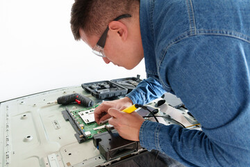 Tv repairman soldering electronic circuit board of a broken led tv in a service center