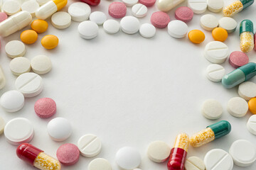 Assorted colorful pharmaceutical tablets and capsules arranged in a circular pattern on a white background