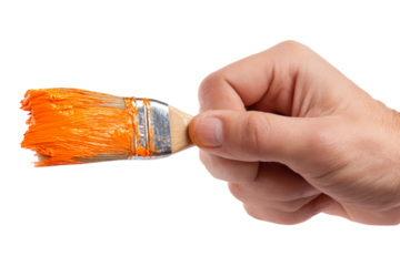 Hand holding a paintbrush loaded with vibrant orange paint against a stark black backdrop, ready for artistic creation isolated on transparent background