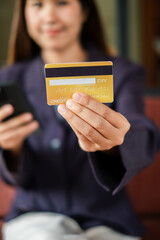 Close-up of a woman holding a credit card and smartphone, symbolizing online shopping or mobile payment.
