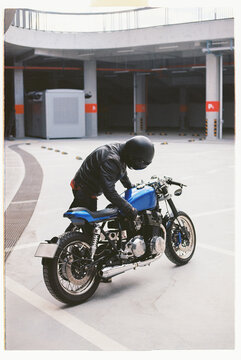 Enthusiast adjusts vintage motorcycle in modern parking garage