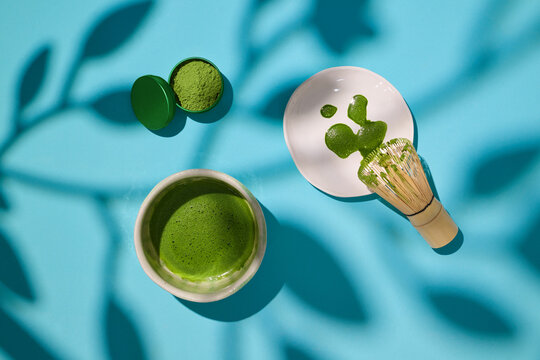 Matcha tea preparation scene with bamboo whisk and powder