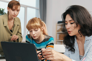 young woman working with colleagues on laptop, focused Gen Z coworkers socializing in modern workplace, business teamwork and collaboration