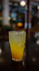  A glass half-filled with an orange-yellow liquid, topped with ice cubes