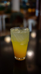  A glass half-filled with an orange-yellow liquid, topped with ice cubes