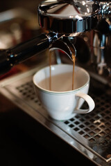 Espresso flows smoothly from a coffee machine portafilter into a white ceramic cup