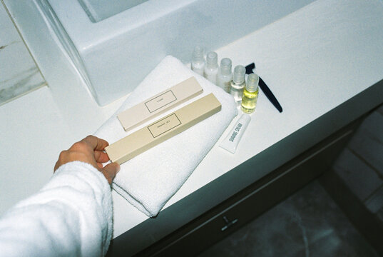 Anonymous woman in a hotel bathroom is about to use a toothbrush.