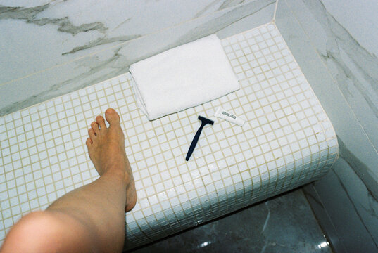 Anonymous woman about to shave her legs in a hotel bathroom.
