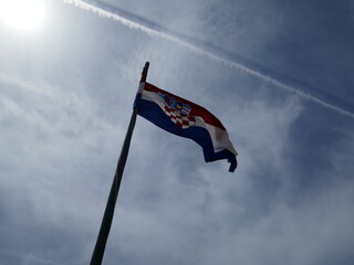 Croatian flag waving high in sky with jet airplane contrails