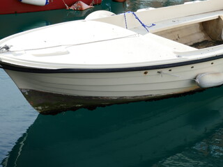Reflection of boat in water with gentle ocean waves rippling on surface
