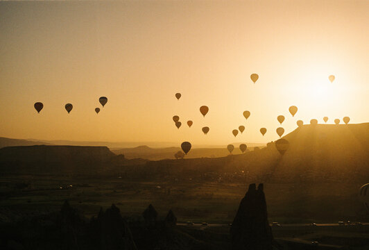 Hot air balloons floating at sunrise over landscape
