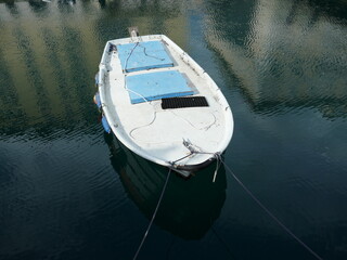 Old utility boat floating on water with reflections
