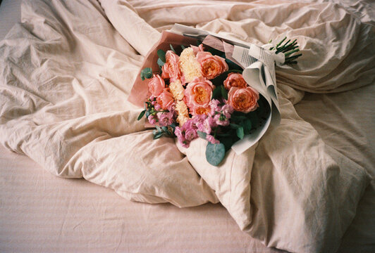 Bouquet of pink and peach flowers on rumpled bed
