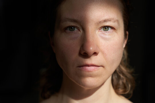 Caucasian female adult in dramatic lighting showing emotion and contemplation.