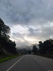 Empty Road at Sunset with Cloudy Sky, Mountain View, and Streetlights in a Calm Rural Area