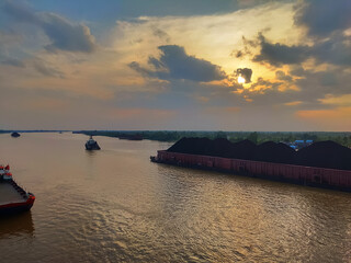 Barges carrying coal on the river with a sunset background