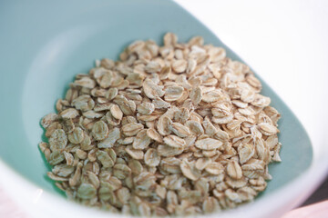 Close-up view of raw oats in a blue bowl on white background.