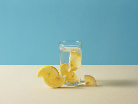 Glass of Lemon-Infused Water on blue and beige background