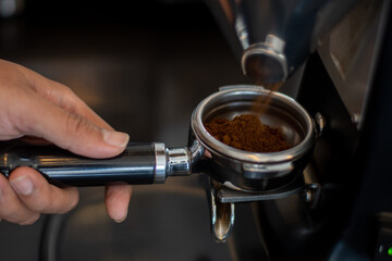 Barista fill the portafilter with coffee grounds to make espresso	