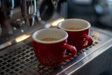 Two red cups of espresso on coffee machine