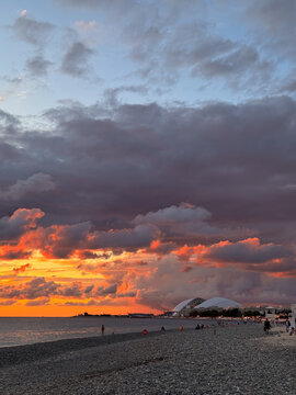 Coastal city beach at sunset with vivid clouds