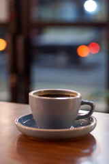 A cup of hot black coffee on the wooden table