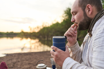Hispanic man having breakfast, enjoying a cup of freshly brewed coffee with cookies on the bank of...