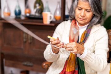 Senior woman knitting with white yarn and needle at home