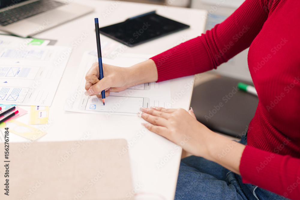 Wall mural ui ux designer at work asian woman hand sketching mobile app interface wireframe for website design 