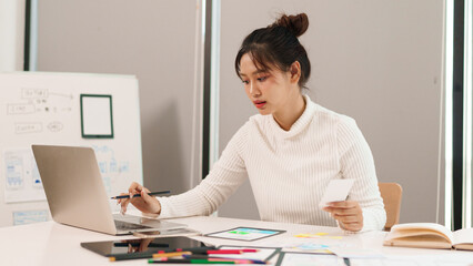 Asian woman UI UX designer working on laptop creating interface design for mobile app website...