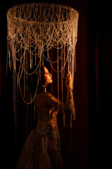 Young Caucasian circus performer or burlesque dancer in golden vintage corset, front view, posing...