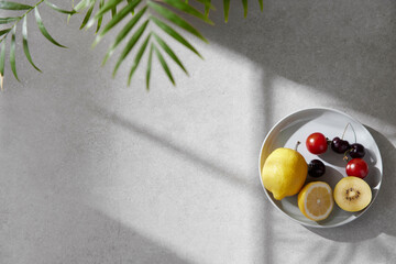 A cozy backdrop with fresh fruits and grass on a table with natural sunlight and shadows.