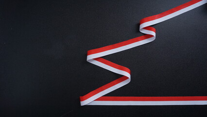 Indonesia independence day celebration concept with red and white ribbon as symbol of Indonesia flag isolated on black background