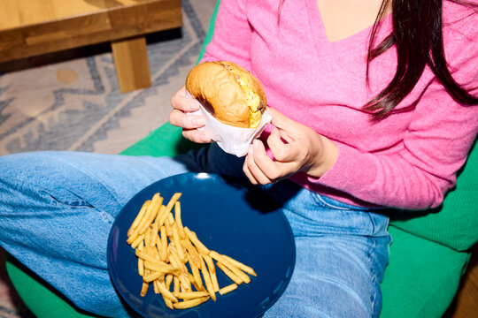 Woman enjoys a burger in the comfort of her home