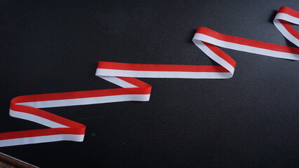 Indonesia independence day celebration concept with red and white ribbon as symbol of Indonesia flag isolated on black background