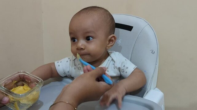 Baby boy eating with mother. baby son eats on a feeding chair dirty face. happy kids dream family weaning concept, baby newborn eats. 4K Video