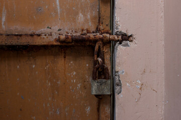 Rusty, Weathered Metal Door Secured By Heavy, Corroded Bolt And Padlock, Old Or Abandoned Entrance