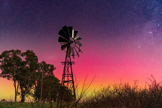 Aurora Australis and the Milky Way in the sky above a farm windmill