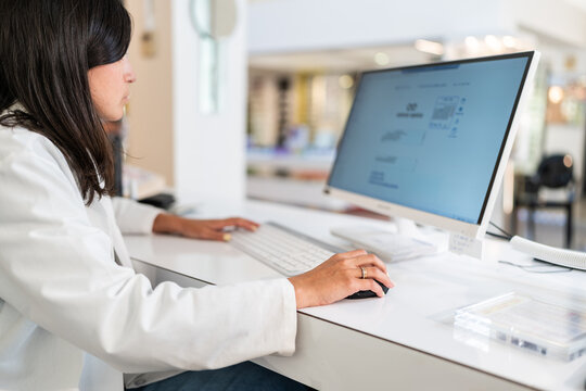 Optician working on computer in modern optical store
