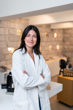 Portrait of smiling optician posing with crossed arms in optical store