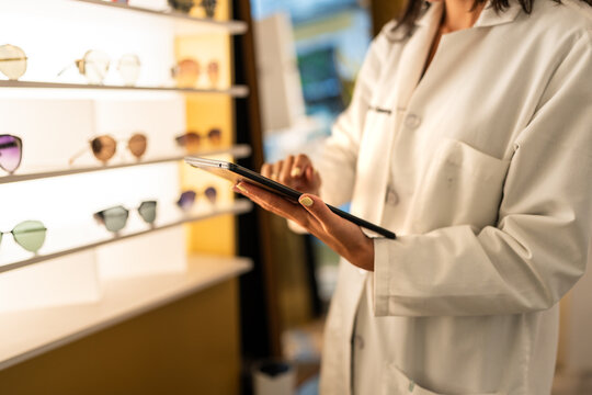 Optician using tablet and managing sunglass inventory in optical store
